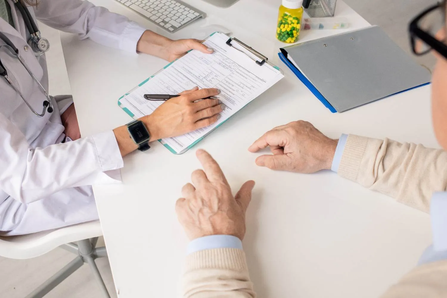 A doctor pointing out a line on a Medicare form to an older patient